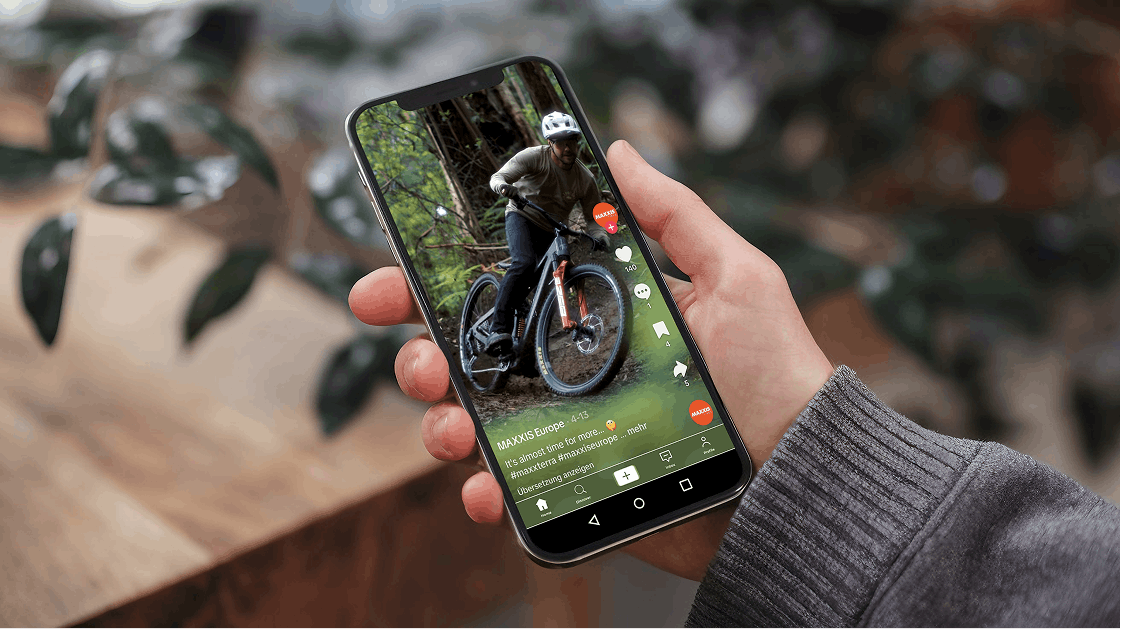 Hand hält Smartphone mit Social-Media-Video eines Mountainbikers im Wald